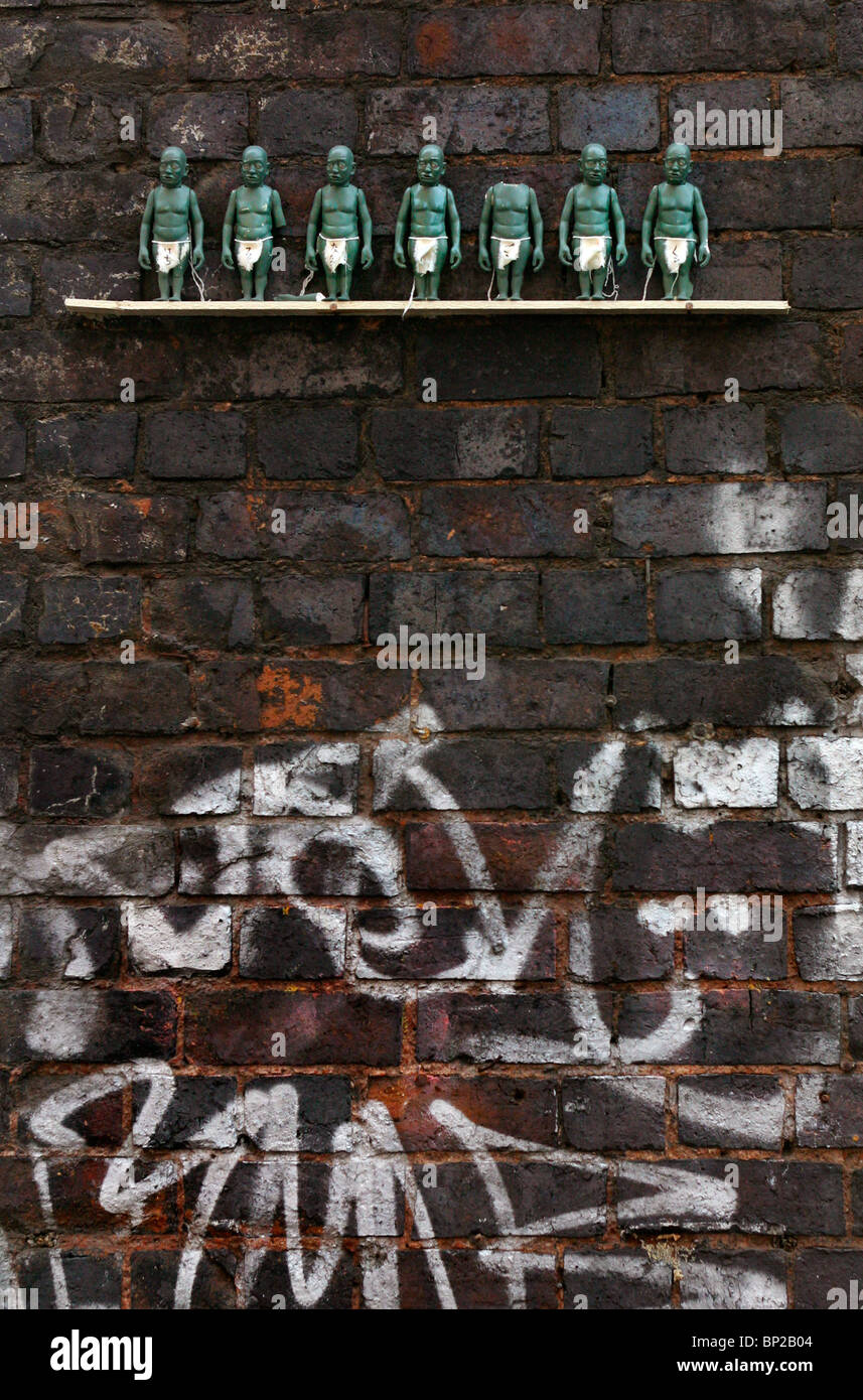 Kleinen grünen Figuren auf einem Regal 10 ft hoch auf der Innenseite einer Eisenbahn Brücke, London, Brick Lane. Stockfoto