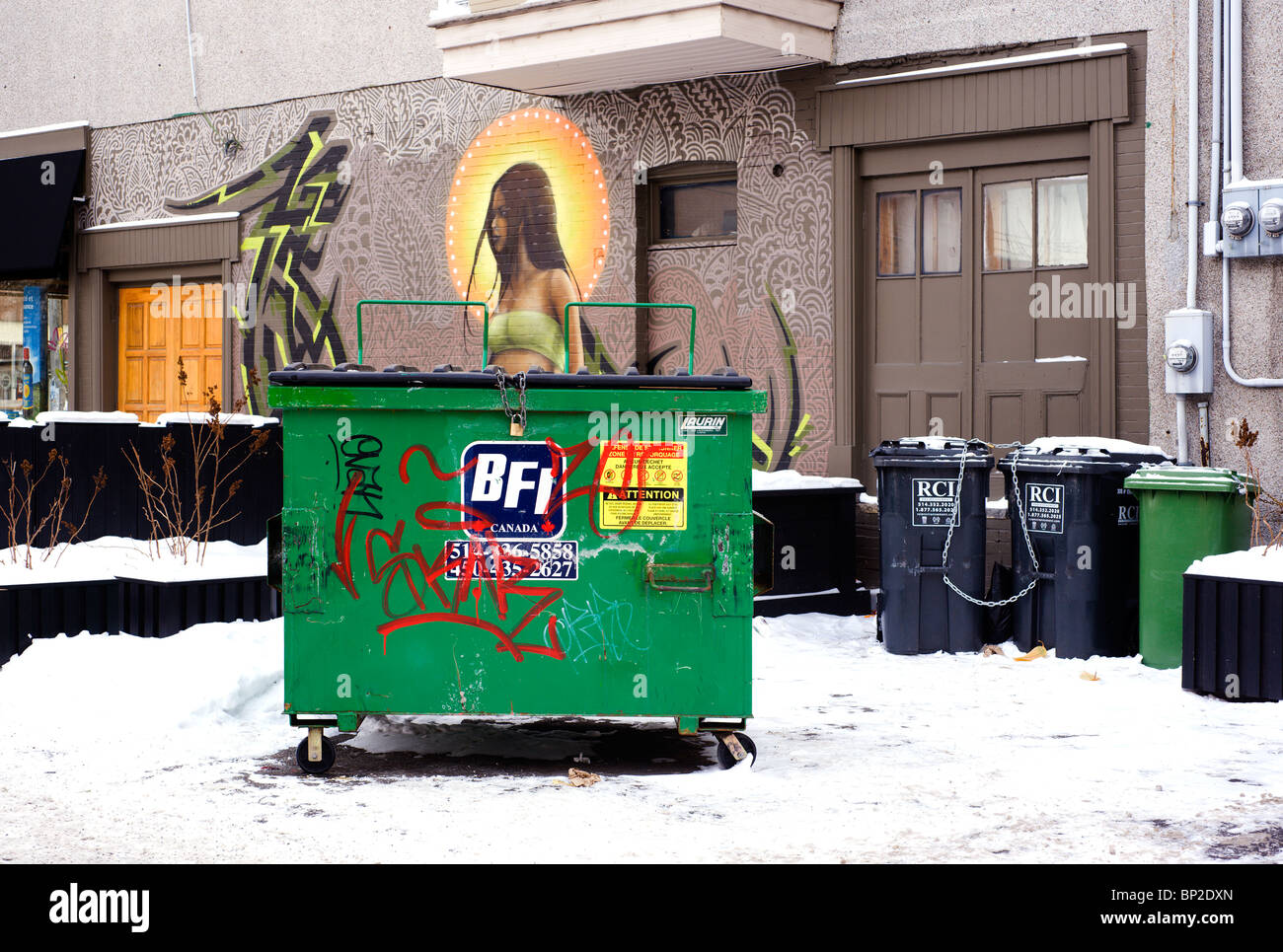 Müllcontainer und recycling-Container auf den Vorgarten eines Montreal-Gebäudes mit einem aufwendigen Murale Gemälde geschmückt. Stockfoto