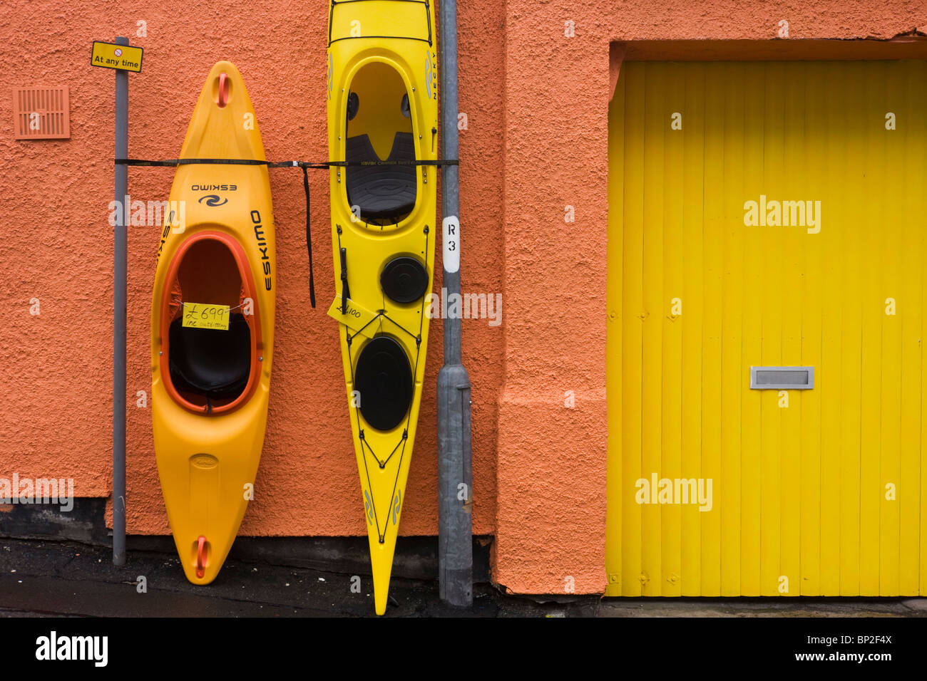 Kajaks und Kanus stehen aufrecht an einer Shop-Wand in Oban, Schottland. Stockfoto
