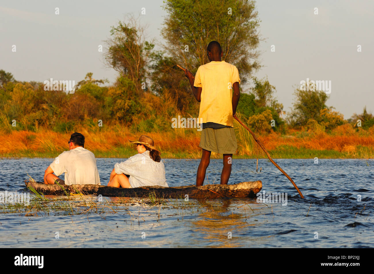Poler mit Touristen in einem traditionellen Mokoro verfasse auf Exkursion in das Okavango Delta, Botswana Stockfoto
