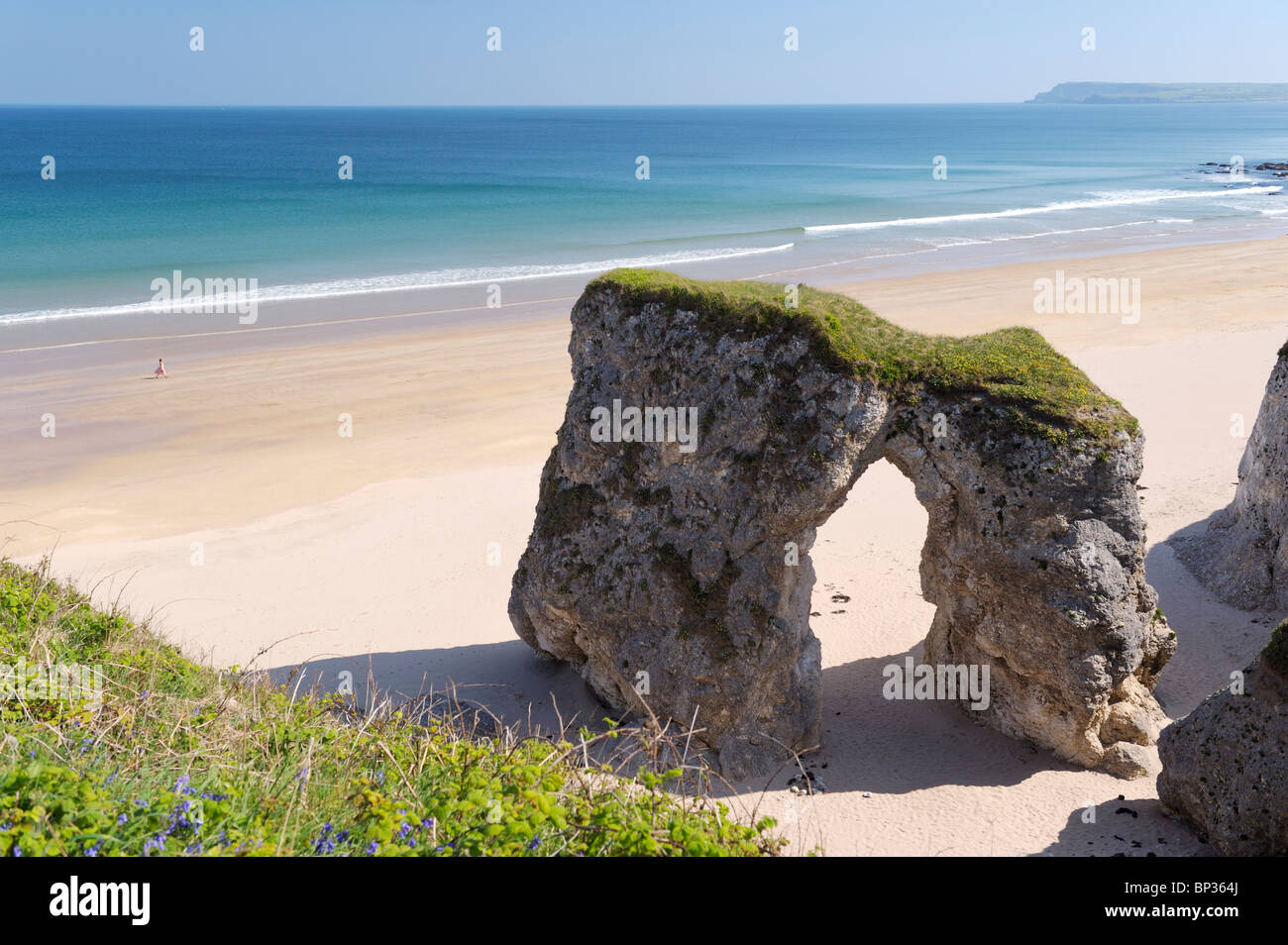 Junge Frau Spaziergänge am einsamen Strand an den weißen Felsen zwischen Portrush und Bushmills, Nordirland. Erodierte Kalksteinfelsen Stockfoto