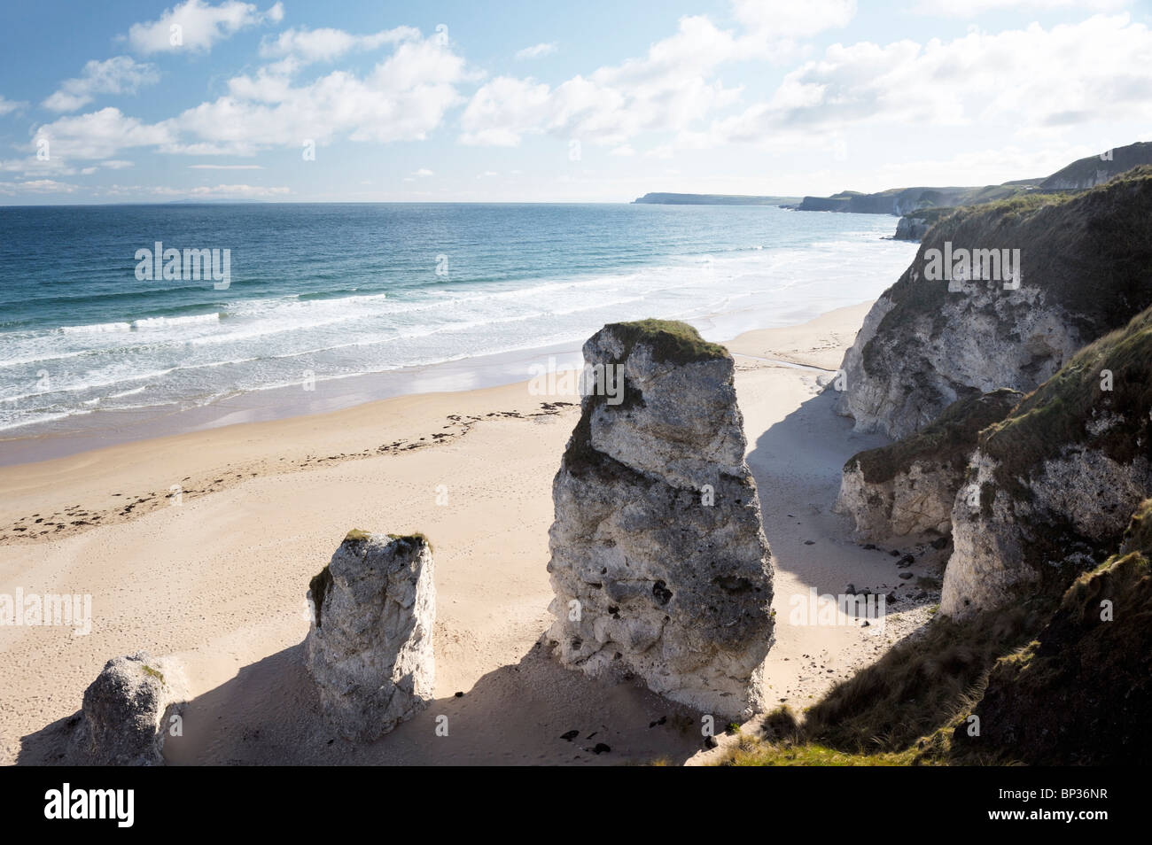 Verlassener Strand mit Fußspuren auf den weißen Felsen zwischen Portrush und Bushmills, Nordirland. Erodierte Kalksteinfelsen Stockfoto