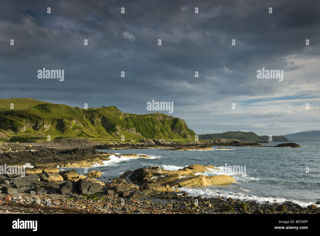 Wellen brechen sich an einem wilden felsigen Küstenstreifen auf der Insel Seil, Schottland Stockfoto