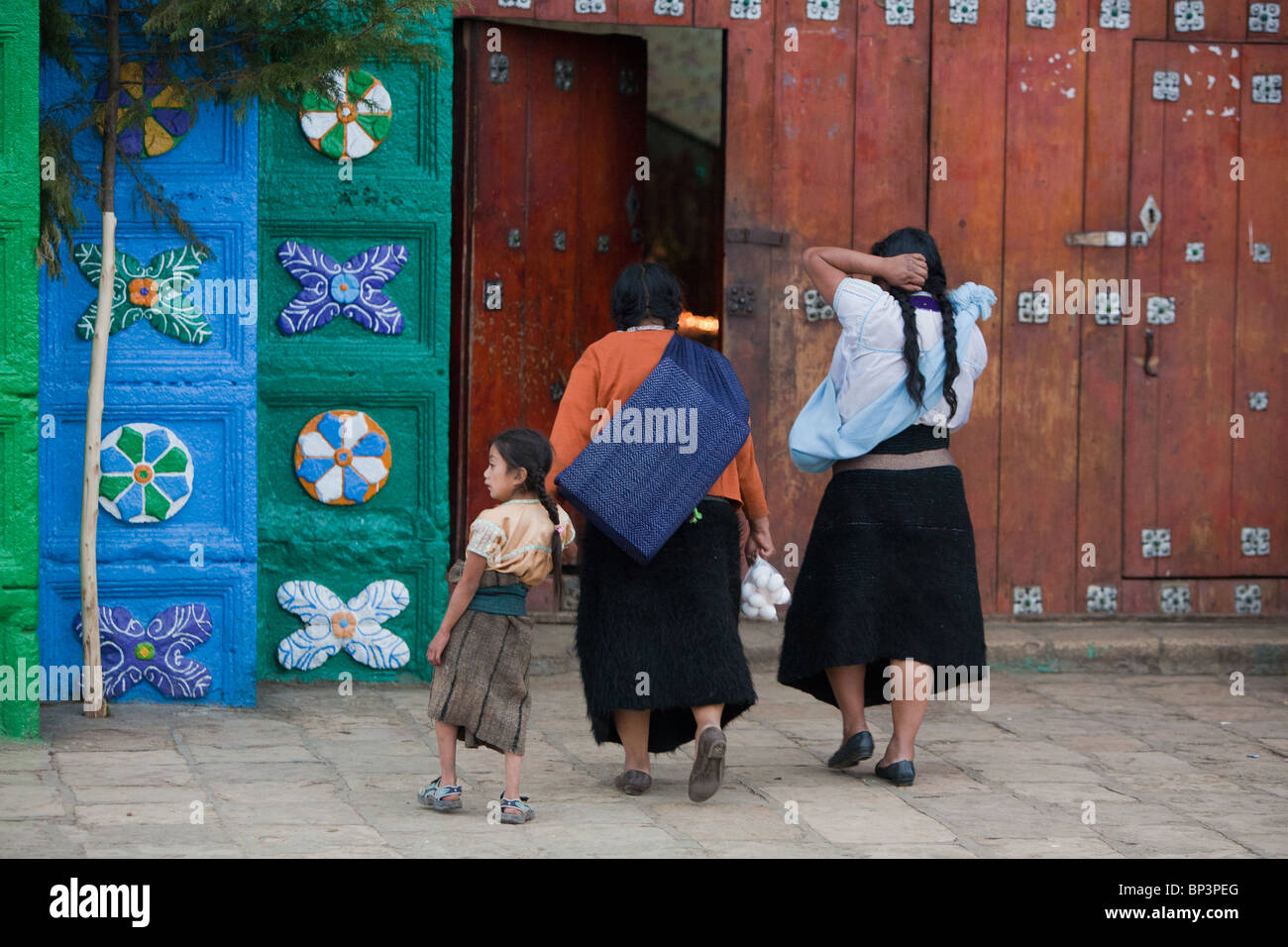 Zwei Chamulan indigene Frauen und ein kleines Mädchen gehen im Inneren der Kirche in San Juan Chamula, Chiapas, Mexiko Stockfoto