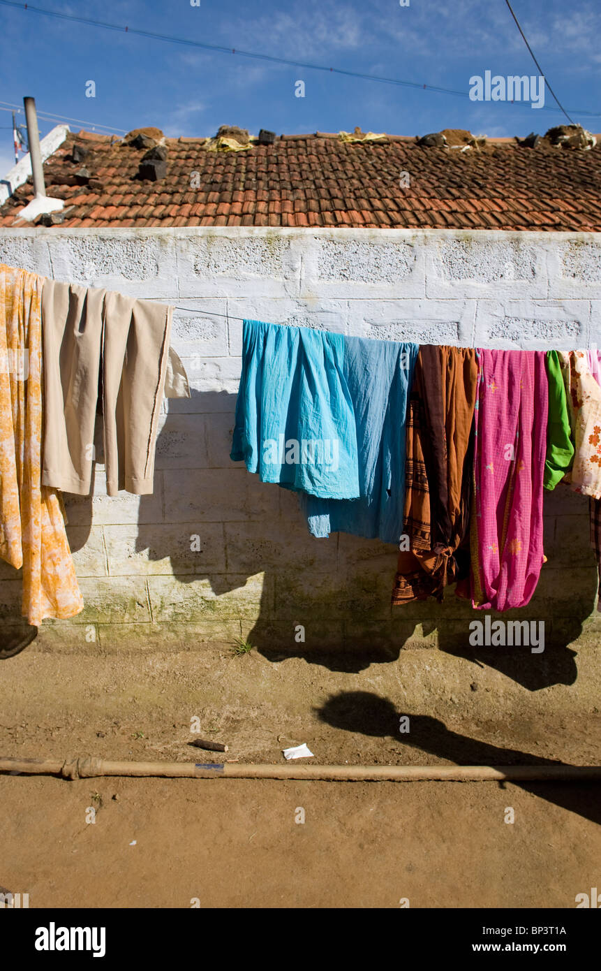 Indische bunte Kleidung trocknen in der Sonne hinter einer Wand in einem kleinen Dorf im Nilgiris Bezirk. Stockfoto