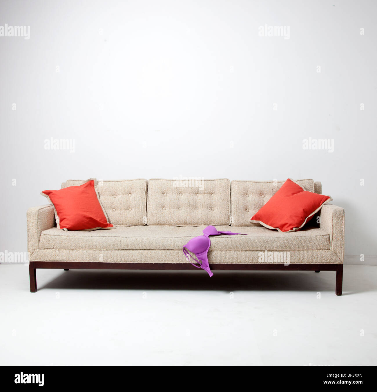 weißen Sofacouch mit lila BH und orange Kissen Stockfoto