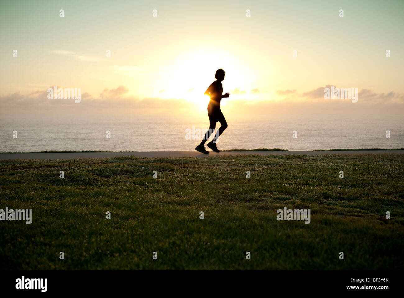 Eine Silhouette von einem Jogger laufen allein mit Sonne am Horizont Stockfoto
