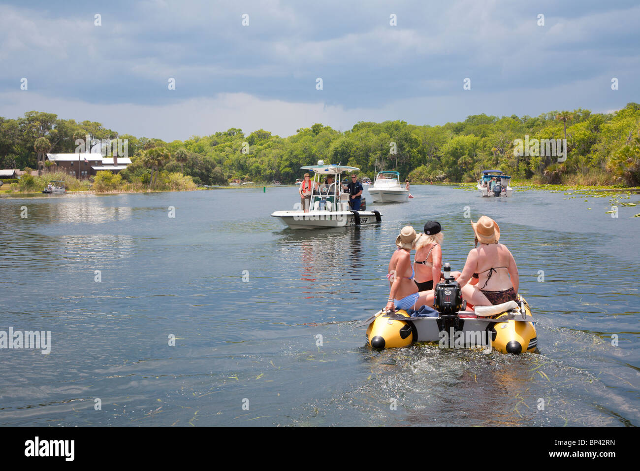 Schlauchboot mit Frauen in Bikinis Durchgang ein county Sheriff Patrouillenboot in Bucht von Lake George in Zentral-Florida Stockfoto