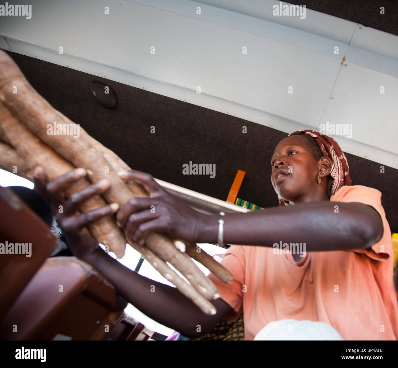 Eine Frau verkauft lange Stücke rohen Maniok an Passagiere im Bus zwischen Segou und Bamako, Mali. Stockfoto