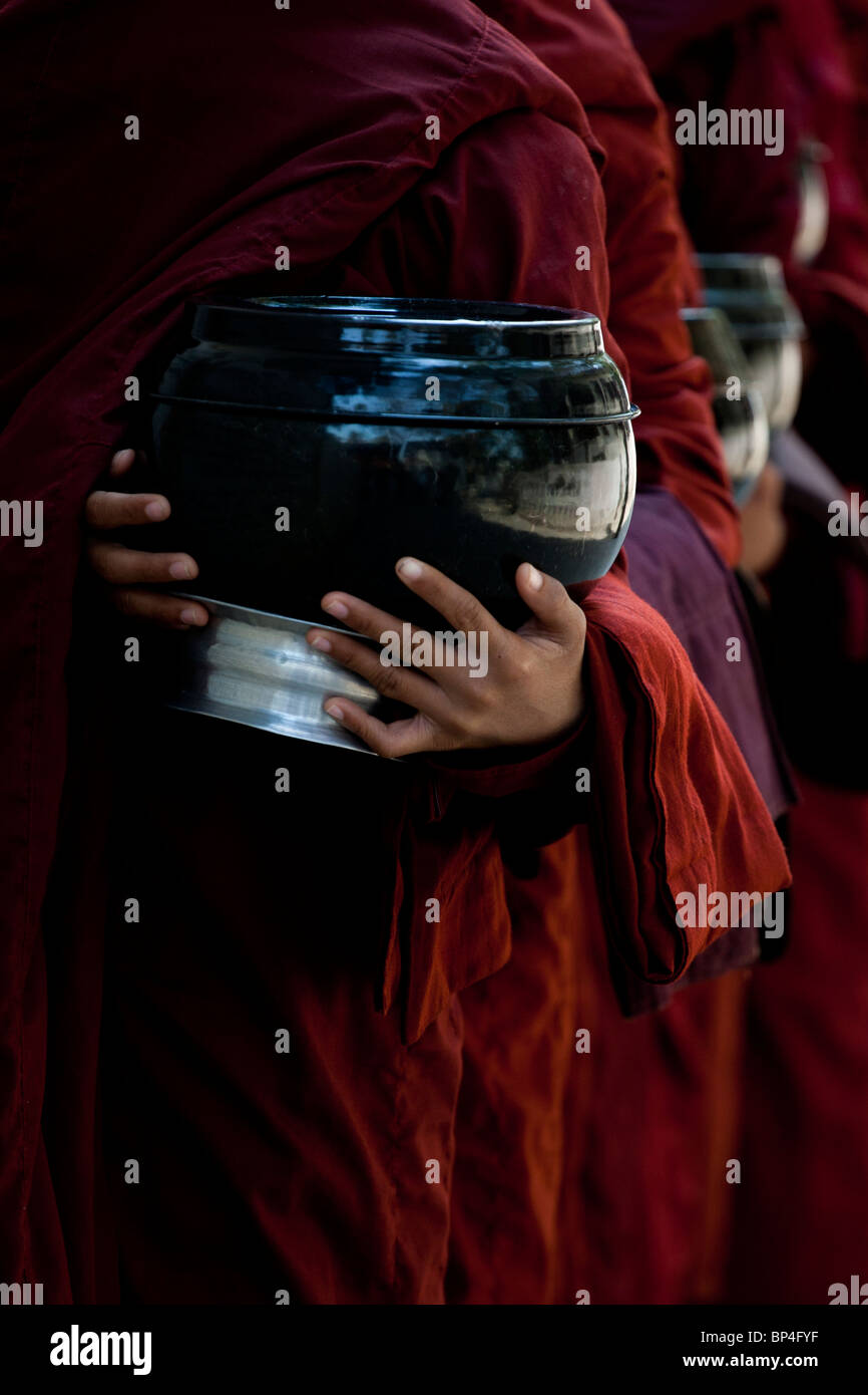 Junge Mönche stehen in der Schlange, Lebensmittel aus der Community rund um das Mahagandayon Kloster in Amarapura, Myanmar zu erhalten. Stockfoto