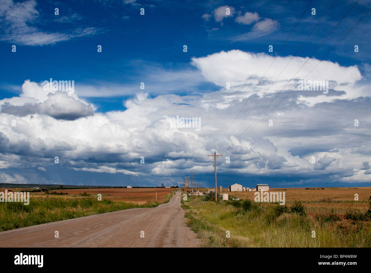 Malerische Szenerie eines Bauernhofes auf einem Schotterweg in einer weiten ländlichen Landschaft mit Cumulus Wolkenformationen im südwestlichen Colorado Stockfoto