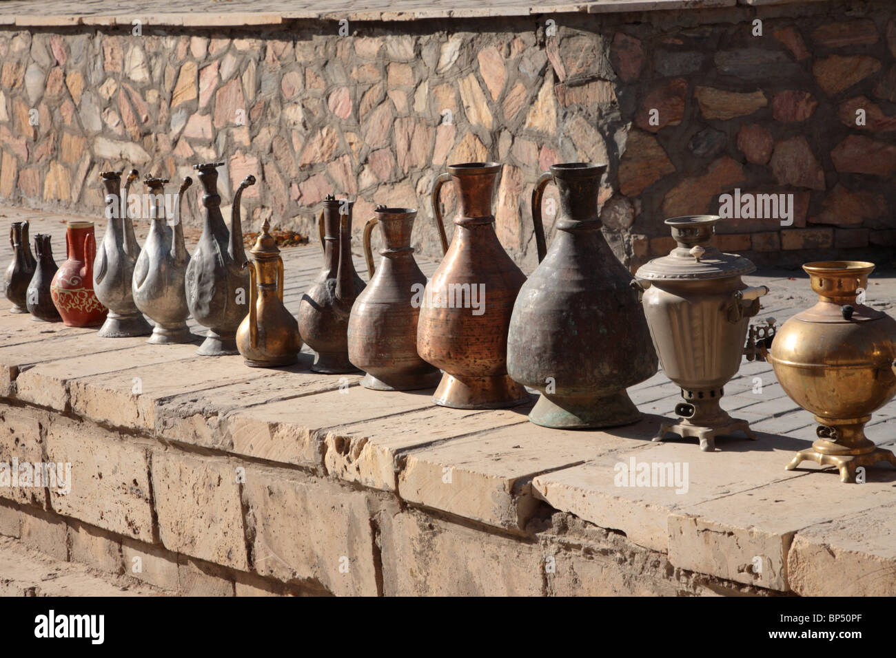 Eine Reihe von metallischen Gläsern entlang einer Wand in Bokhara-Markt in Usbekistan. Stockfoto