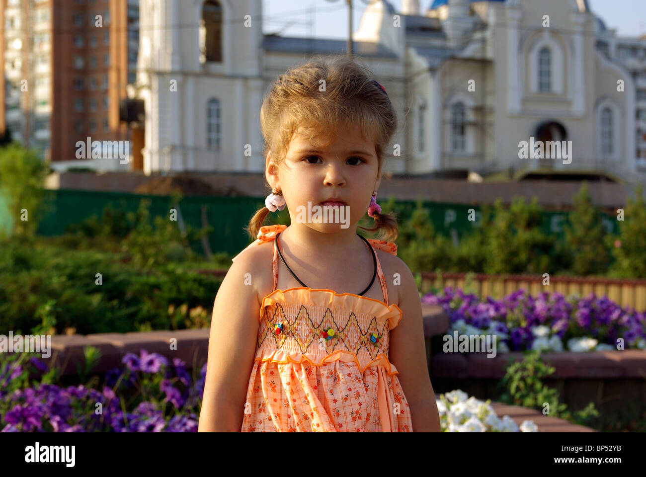 Kleines Mädchen im Park. Blume und Kirche im Hintergrund. Stockfoto