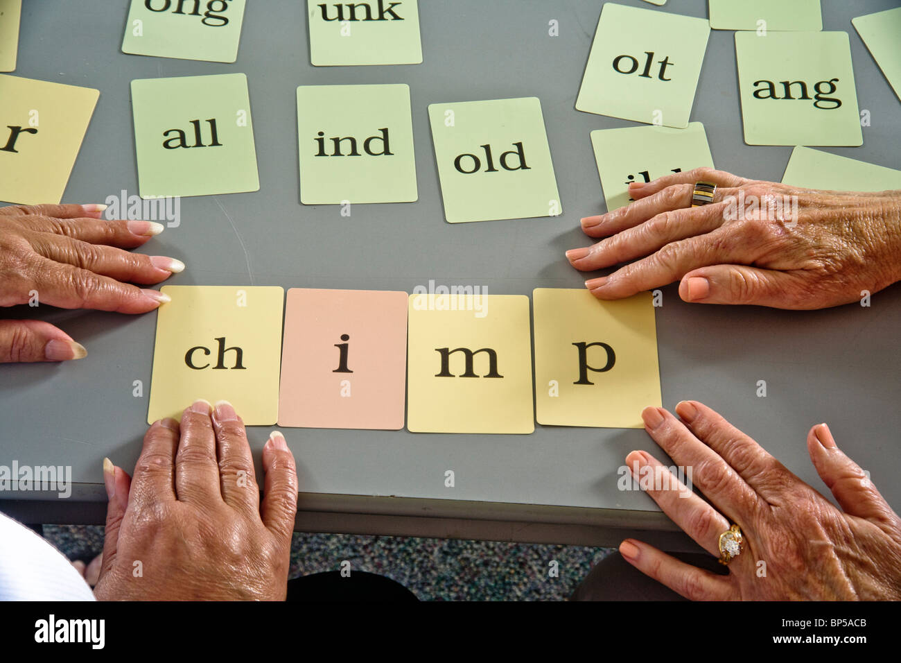 Mit "Wort Karte" Komponenten zu ein ganzen Wort bilden, weist Freiwilligen Erwachsenenalphabetisierung Lehrer ein älterer Student Hispanic. Stockfoto