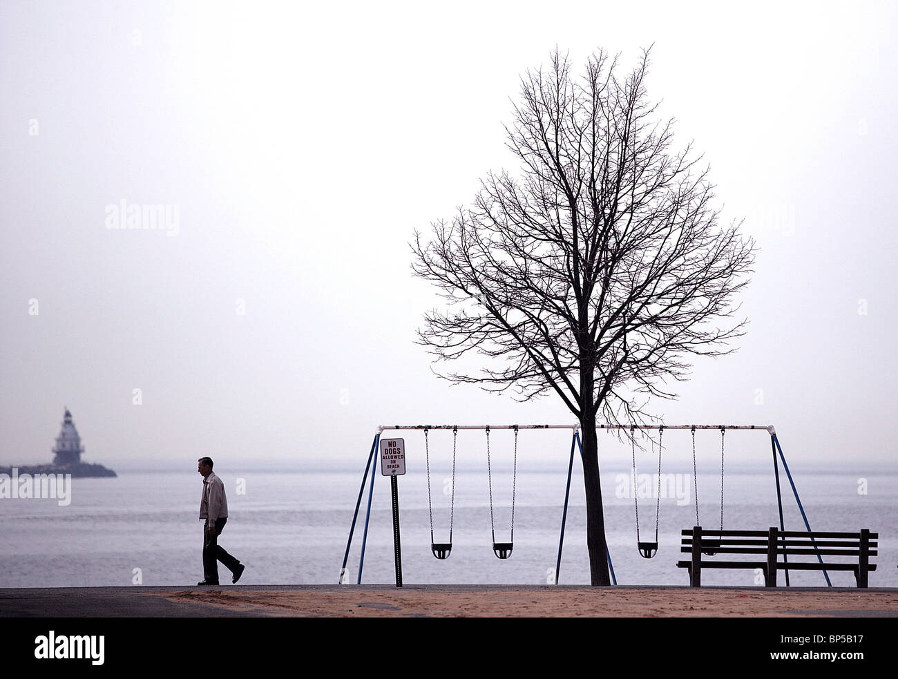 Ein Mann geht an einem leeren Strand im Winter in New Haven Connecticut USA Stockfoto