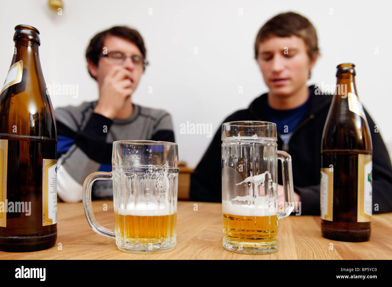 Flaschen und Gläser Bier mit zwei junge Männer im Hintergrund Stockfoto