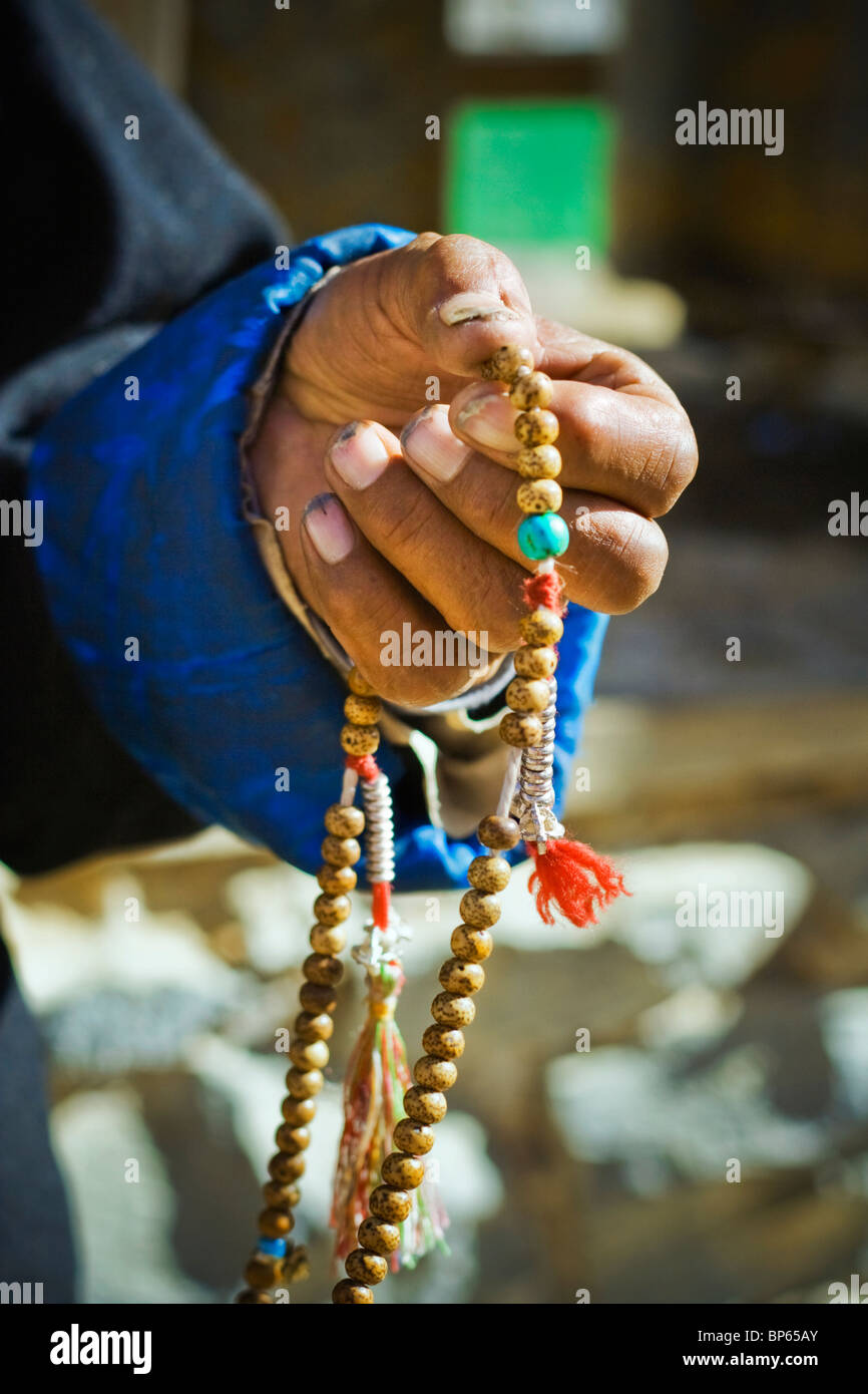 Ein traditionell gekleideter tibetischen Pilger hält sein Gebet/Meditation/Mantra-Perlen Stockfoto