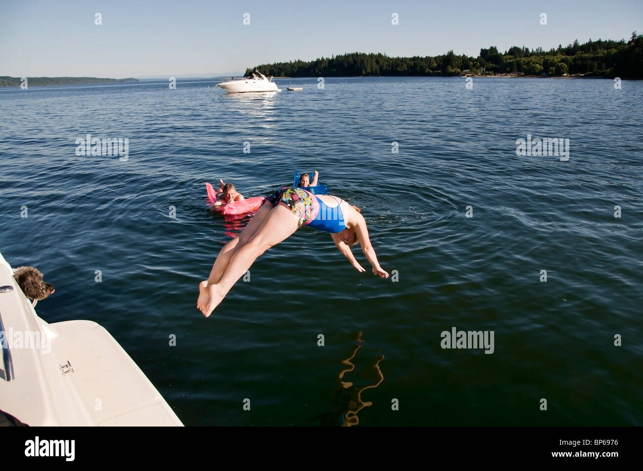 Eine Frau taucht Kopf zuerst in das kalte Wasser des südlichen Puget Sound an einem heißen Sommertag in der Nähe von McMicken Insel aus einem verankerten Boot Stockfoto
