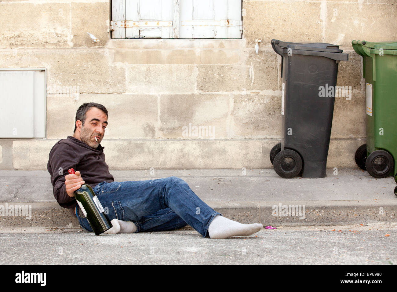 arme Mann betrunken liegen in der Nähe von Mülleimer in Stadtstraße Stockfoto