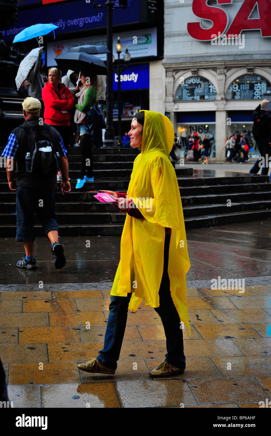 Frauen in gelben Poncho verteilen von Flugblättern im Regen Stockfoto