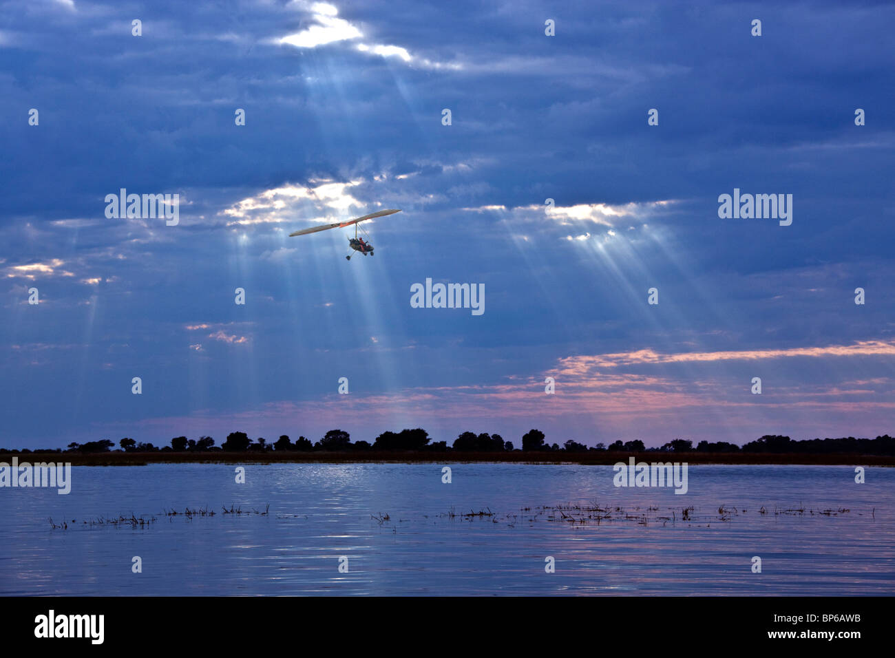 Microlight Flugzeug fliegt niedrig über den Chobe River in Botswana. Stockfoto