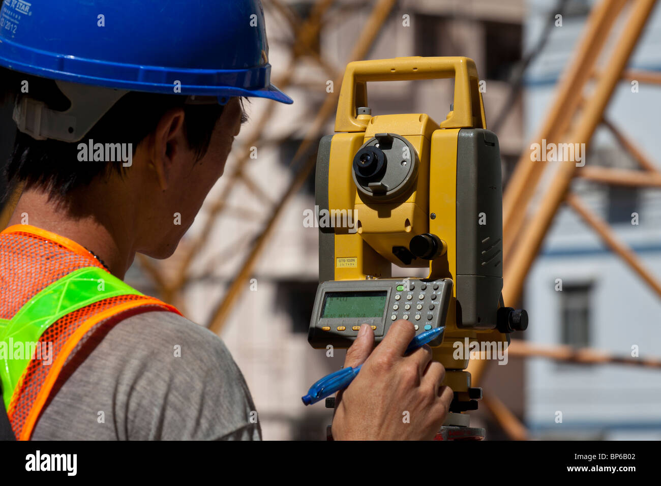 Ein Ingenieur unter Lesungen aus einem Theodolit auf einer Baustelle in Hong Kong. Stockfoto