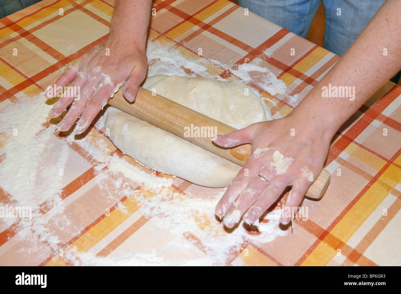 eine junge Frau rollt Pizza / Teig mit einem hölzernen rolling pin. Stockfoto