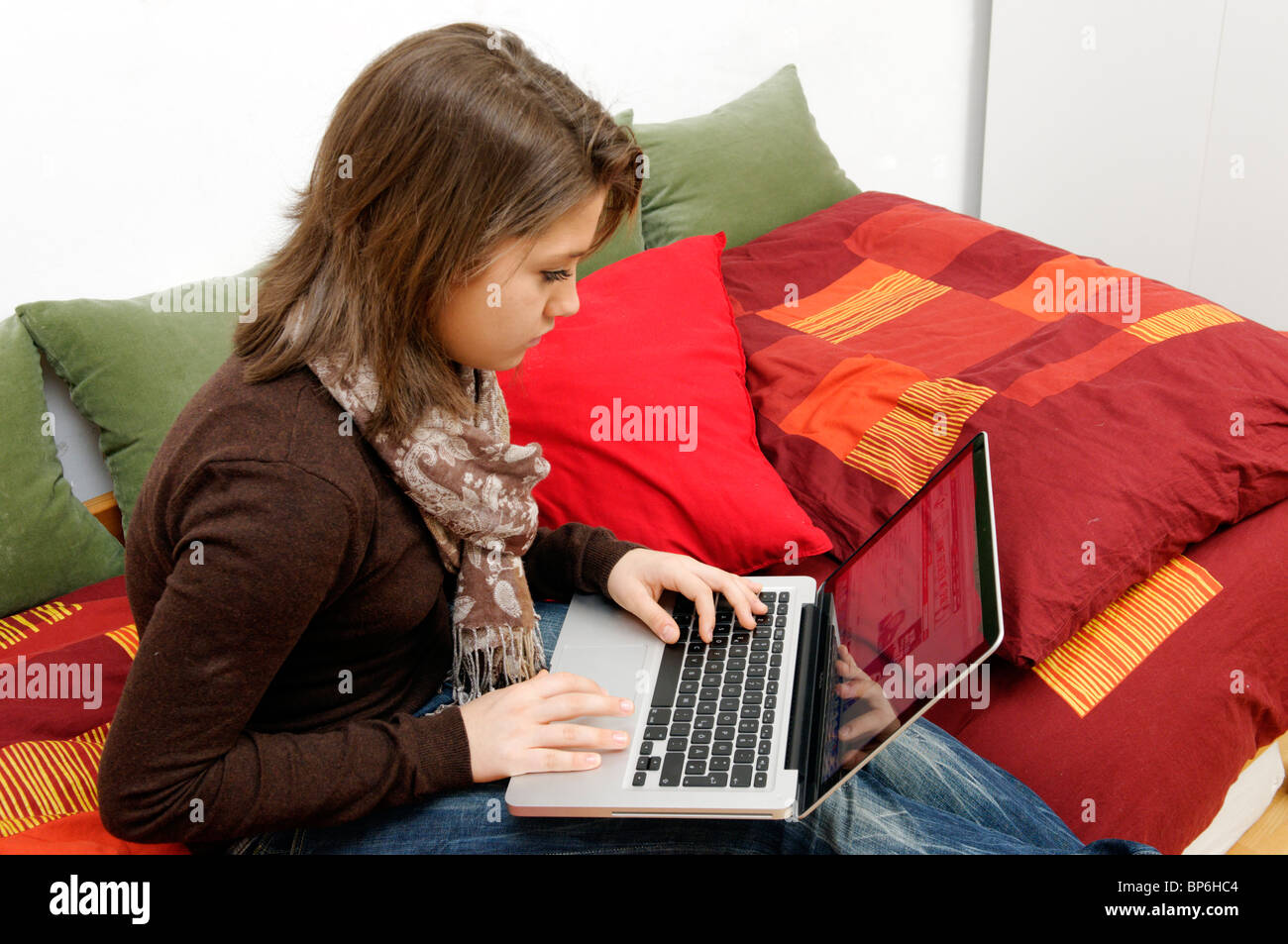 Teenager-Mädchen sitzen auf einer Couch auf ihrem Laptop arbeiten Stockfoto