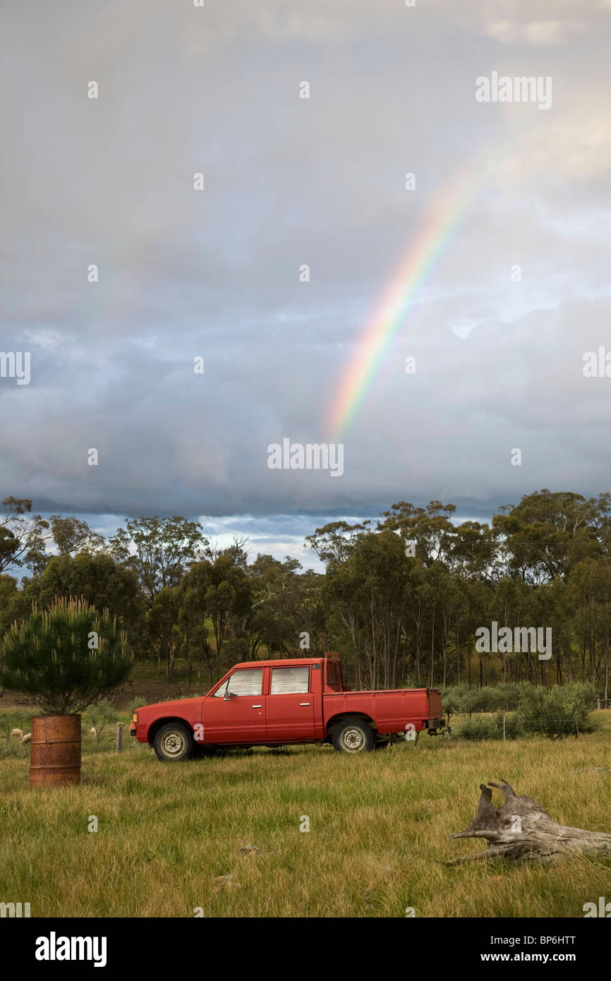 Ein Regenbogen am Himmel über einen Pick-up-Truck in einem Feld Stockfoto