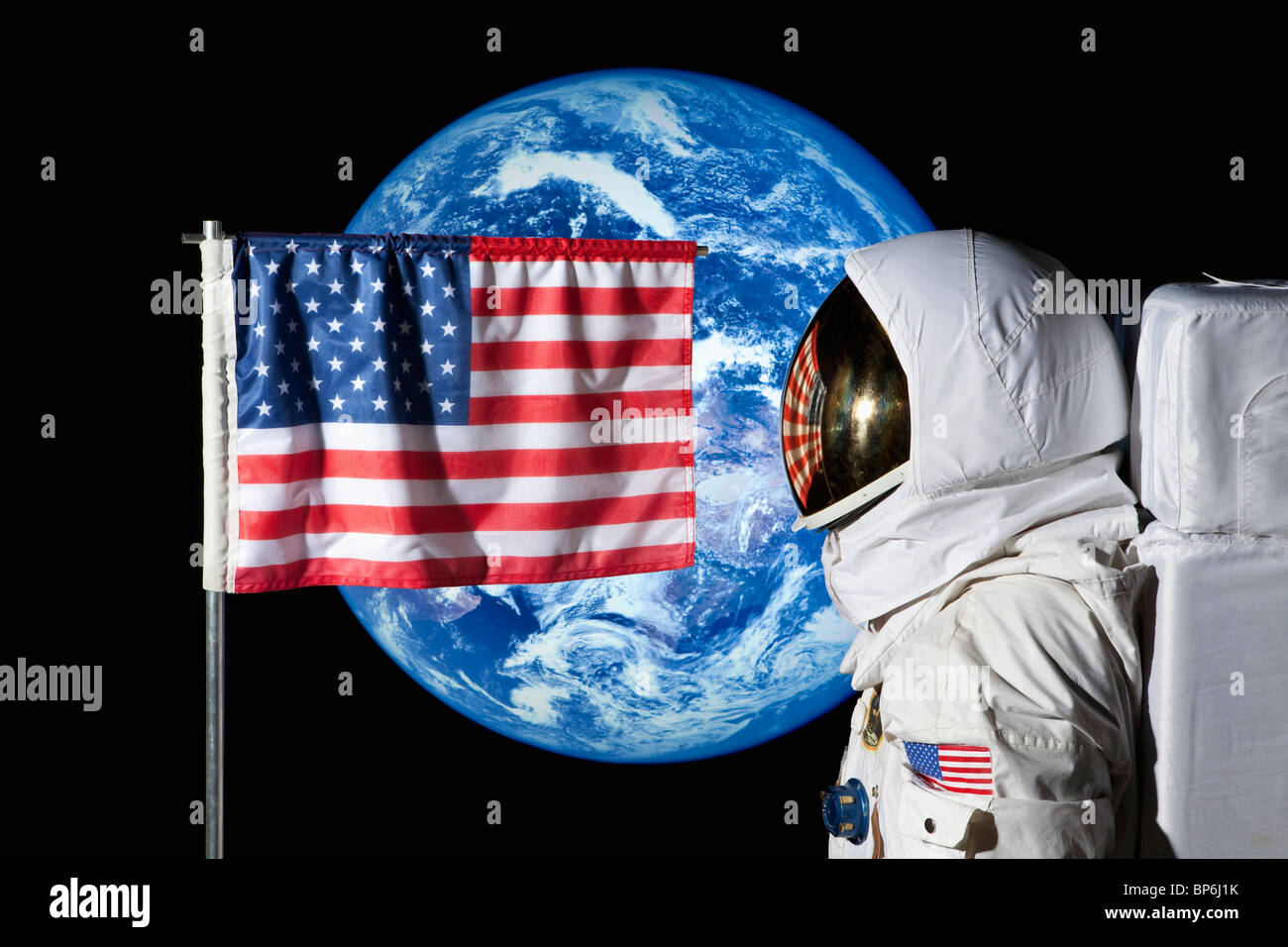 Ein Astronaut durch eine amerikanische Flagge mit der Erde im Hintergrund stehen Stockfoto