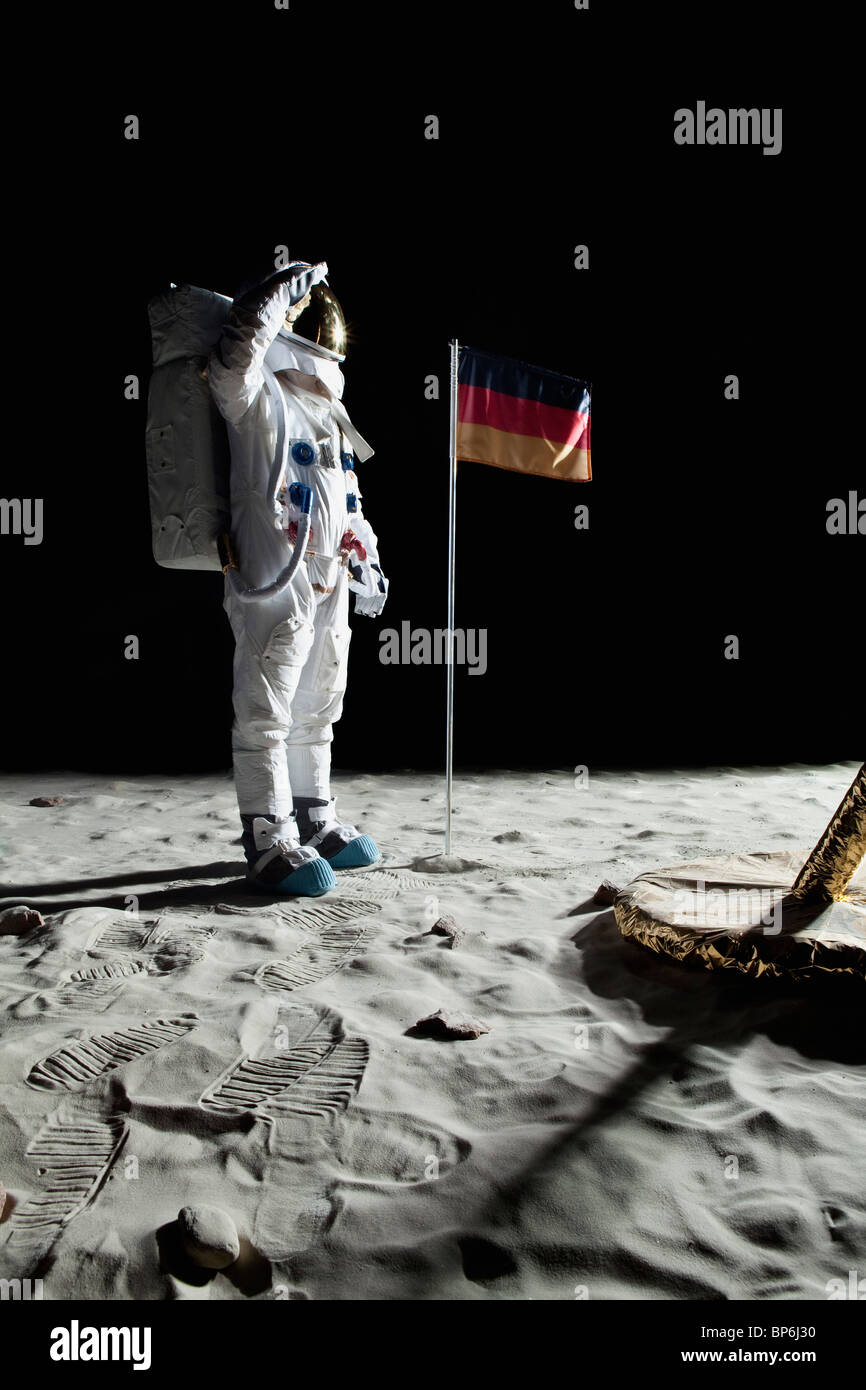 Ein Astronaut Stand in der Nähe einer Mondlandefähre grüßt eine deutsche Flagge Stockfoto