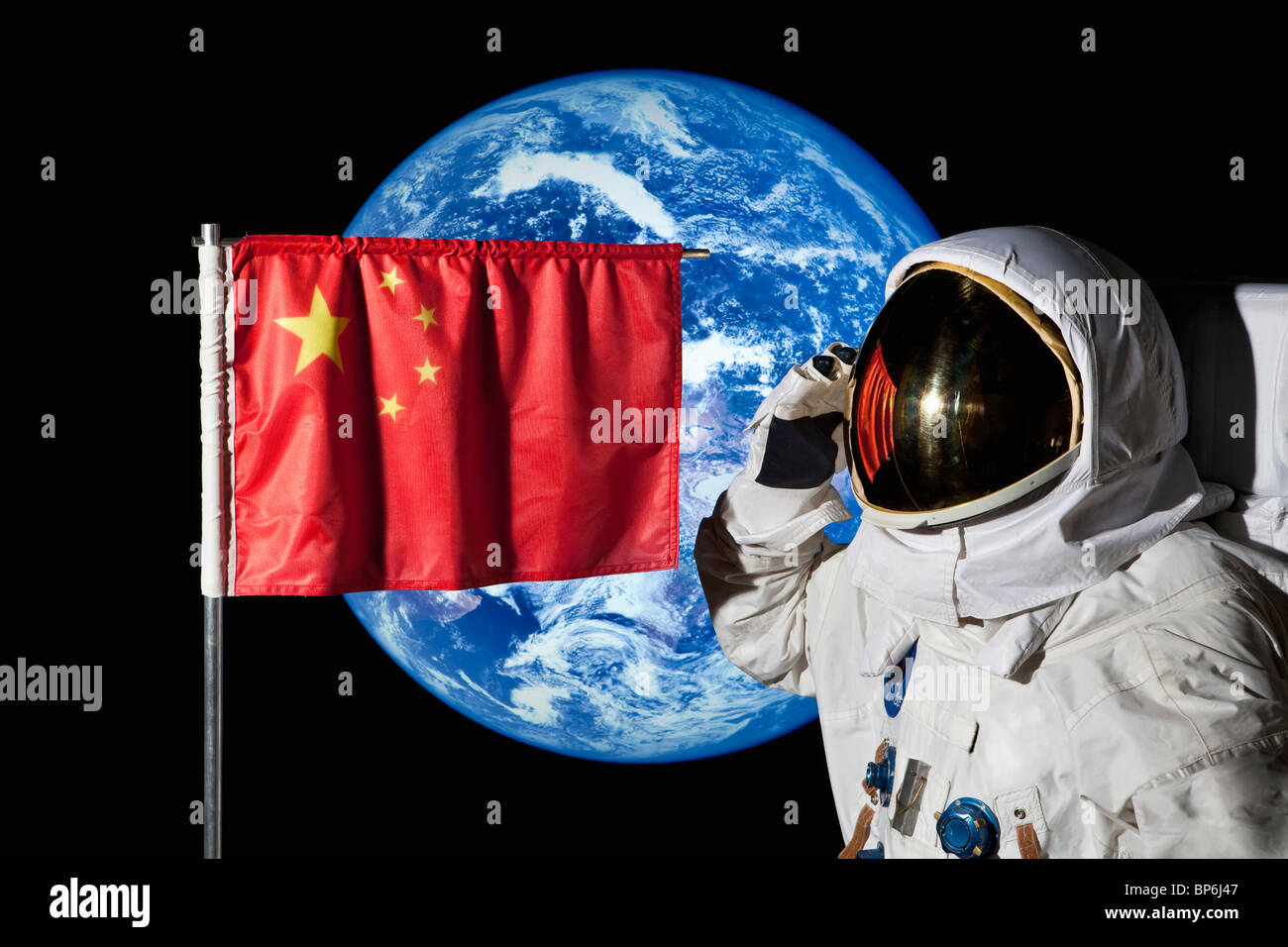 Ein Astronaut, salutieren, eine chinesische Flagge mit der Erde im Hintergrund Stockfoto