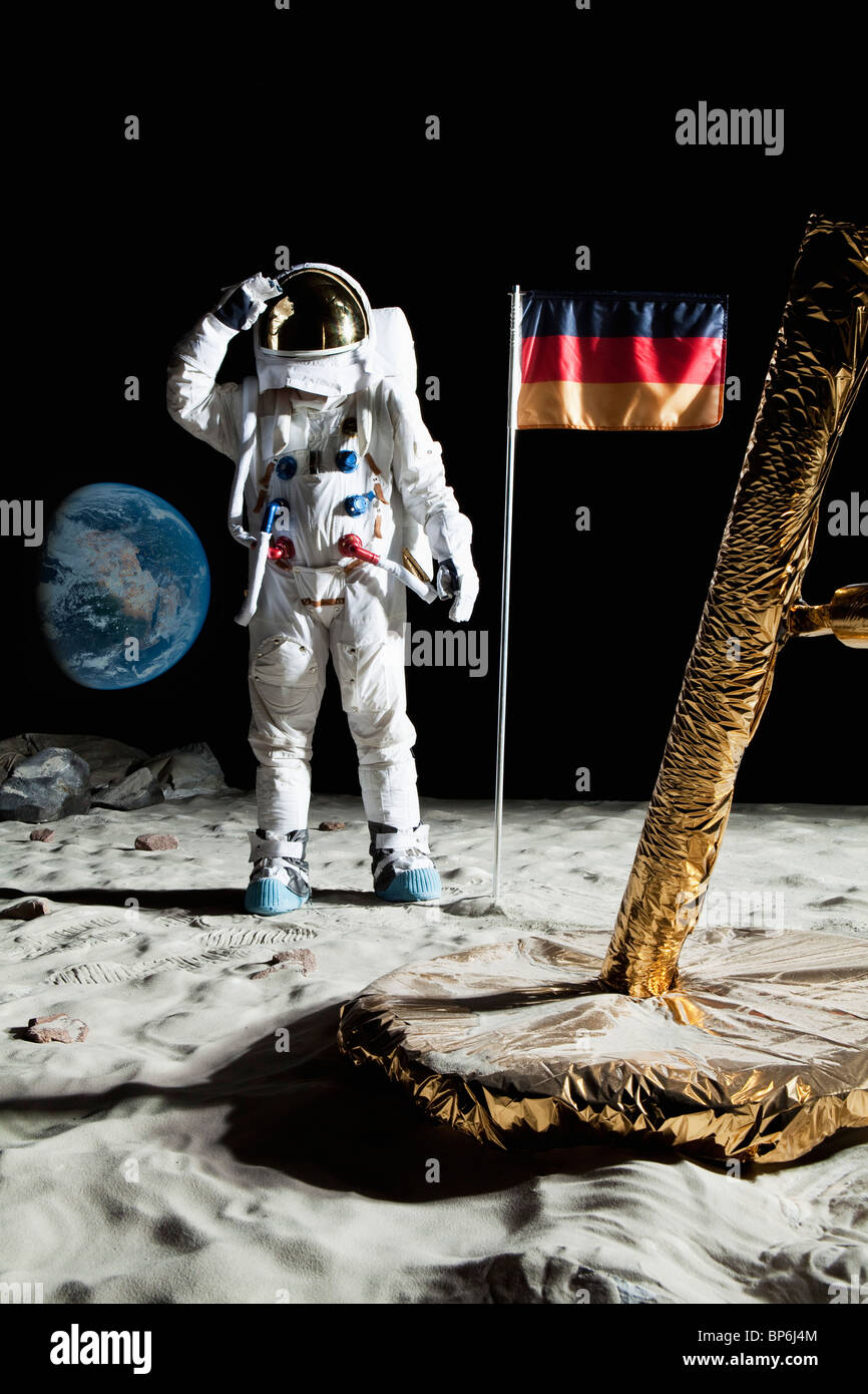 Ein Astronaut Stand in der Nähe einer Mondlandefähre grüßt eine deutsche Flagge Stockfoto