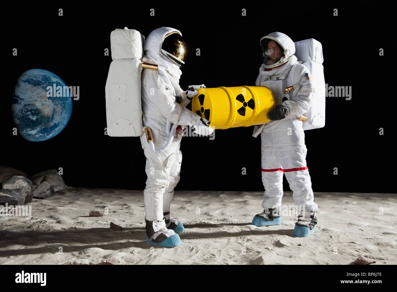 Zwei Astronauten auf der Mondoberfläche mit einer Trommel toxisches material Stockfoto