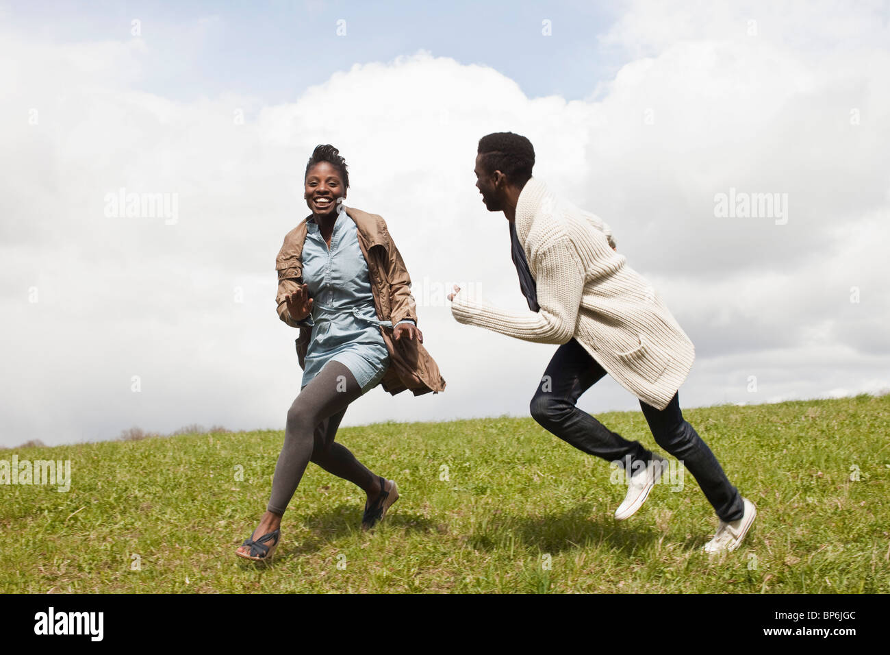Ein junger Mann seine Freundin einen Hang hinunter jagen Stockfoto