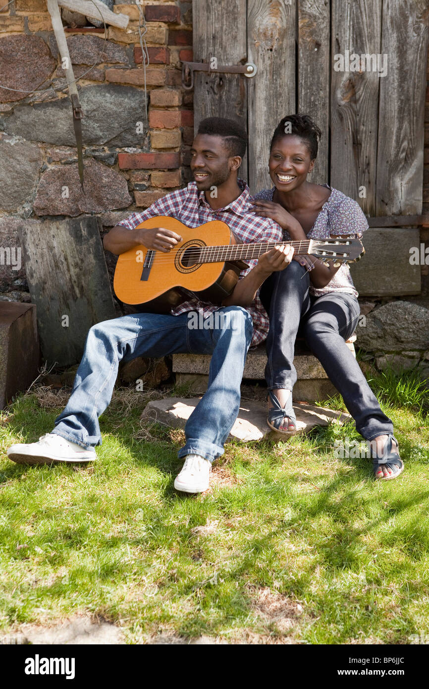 Ein Mann spielt eine akustische Gitarre mit seiner Freundin Stockfoto