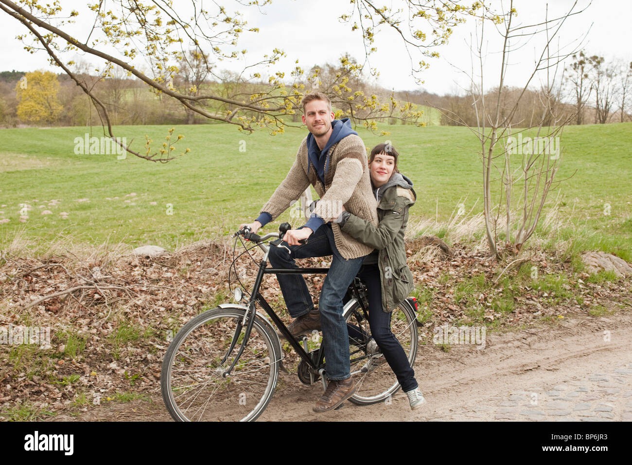 Ein Mann geben eine Fahrt zu seiner Freundin auf dem Fahrrad in das Land Stockfoto