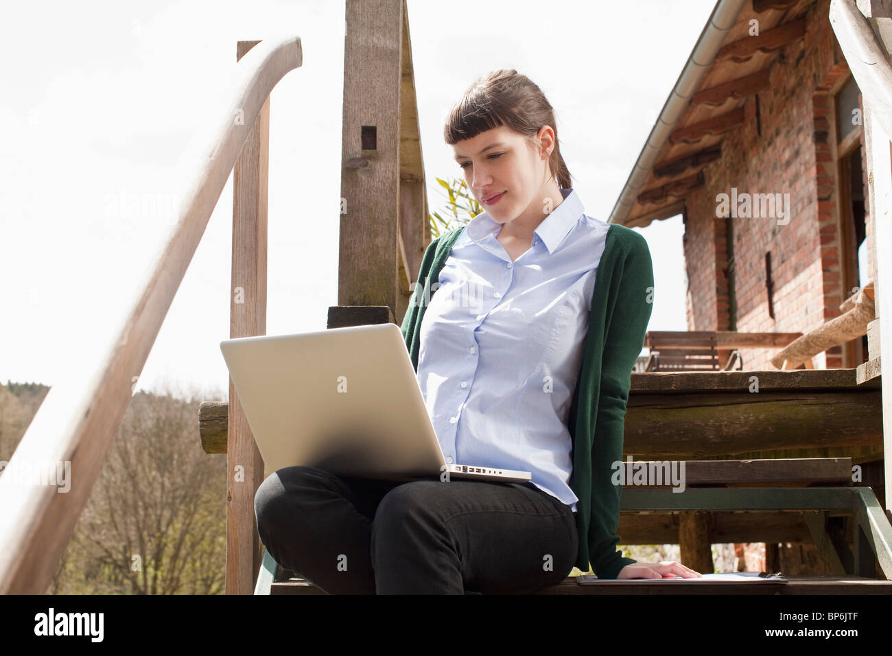 Eine Frau sitzt auf einer Treppe, Blick auf einen laptop Stockfoto