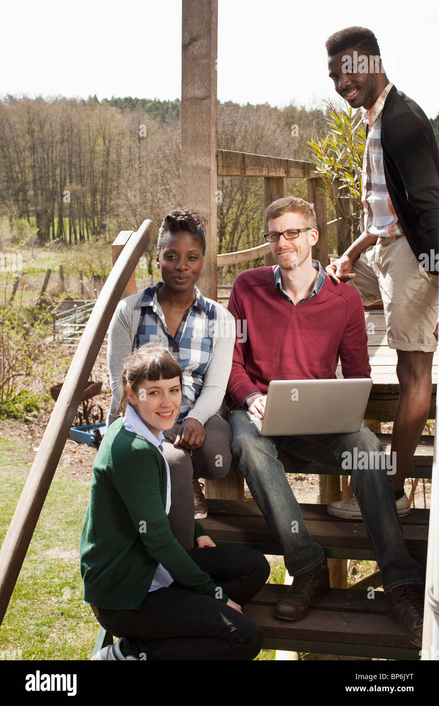 Vier Freunde sitzen auf einer Treppe, die auf der Suche hinter der Kamera Stockfoto
