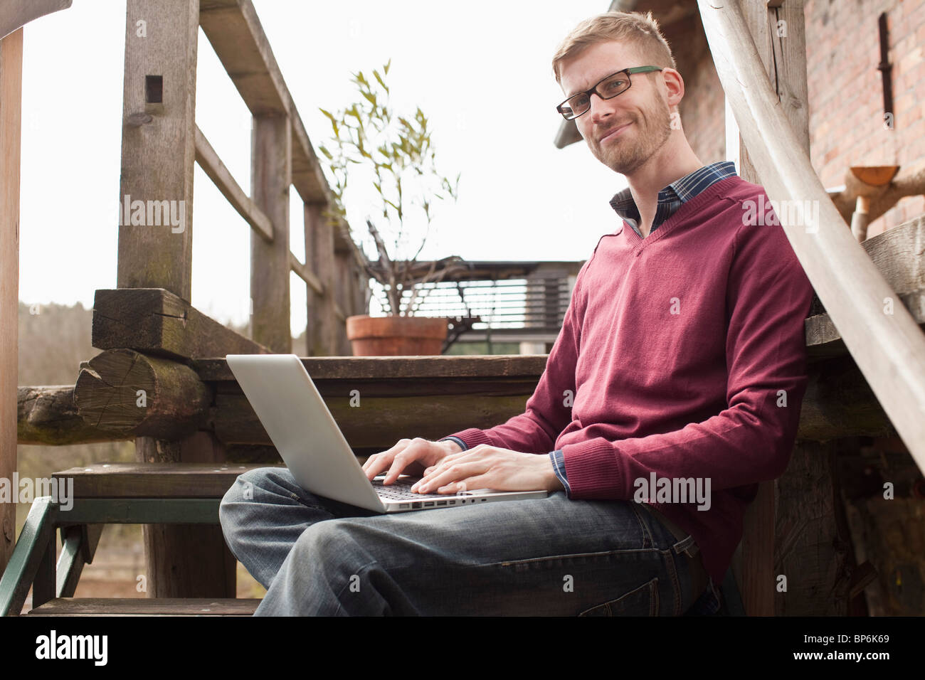 Ein Mann mit einem Laptop sitzt auf einer Treppe Stockfoto