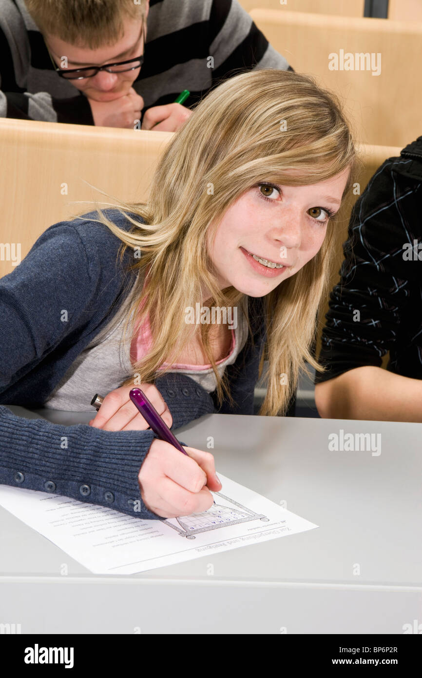 Porträt eines Teenagers tun ein Arbeitsblatt in der Klasse, in die Kamera Lächeln Stockfoto