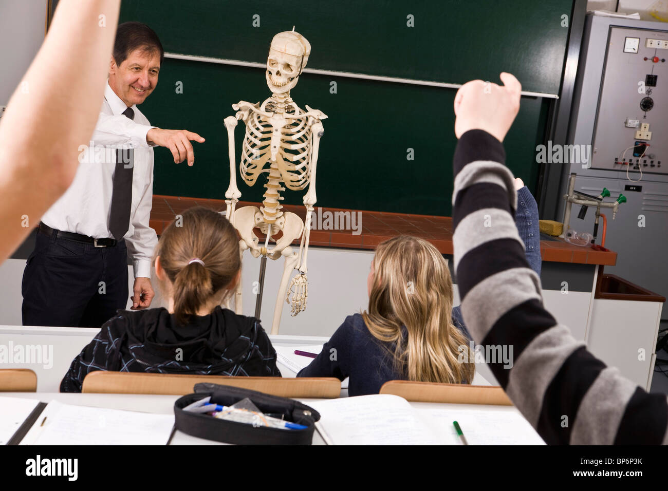 Ein Lehrer zeigt, während seine Schüler heben Sie ihre Hände in einer Biologie-Klasse Stockfoto