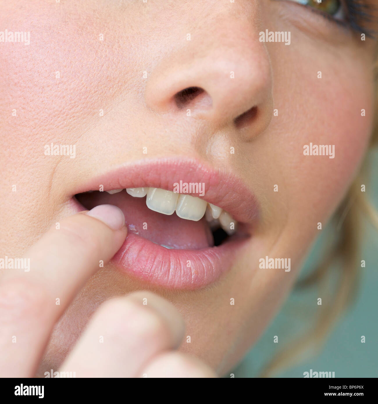 Detail einer Frau ihre Lippen mit einem Finger berühren Stockfoto