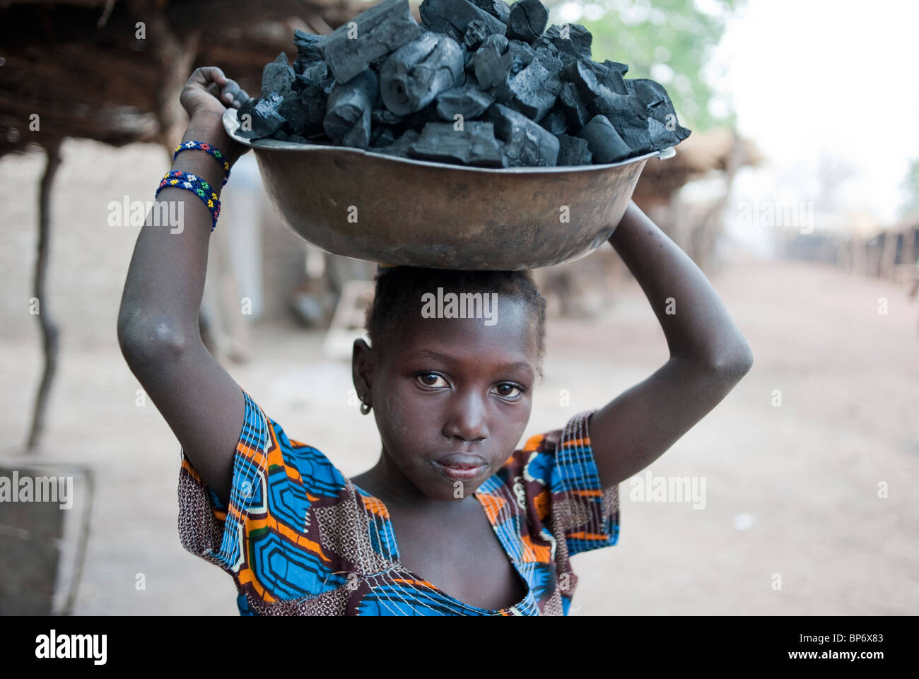 Afrika-Mali - Mädchen tragen Kohle auf den Kopf für den Verkauf als Kochbrennstoff für Küchenherd Stockfoto