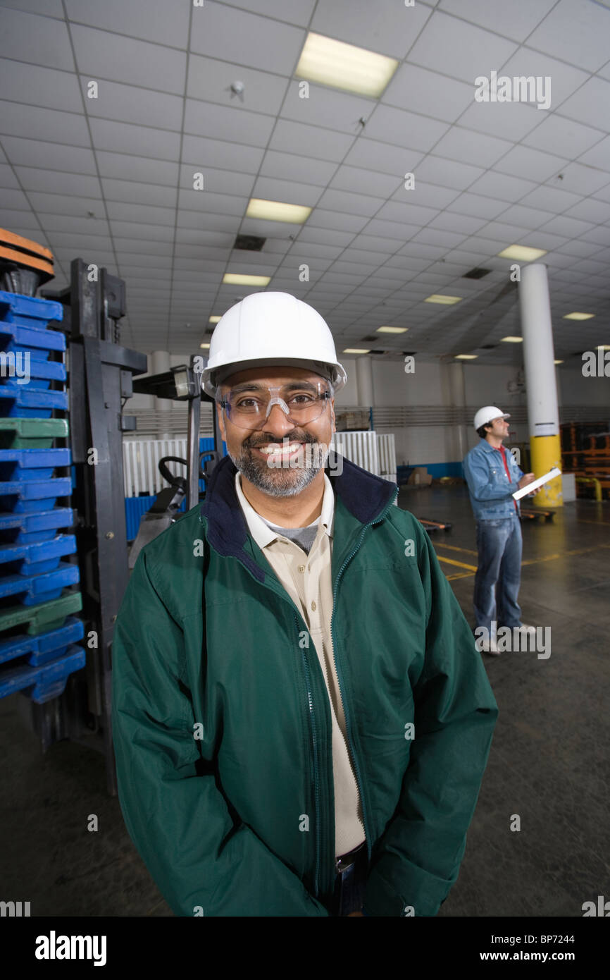 Fröhlicher Mensch stehen in Fabrik, Hart Hut Stockfoto