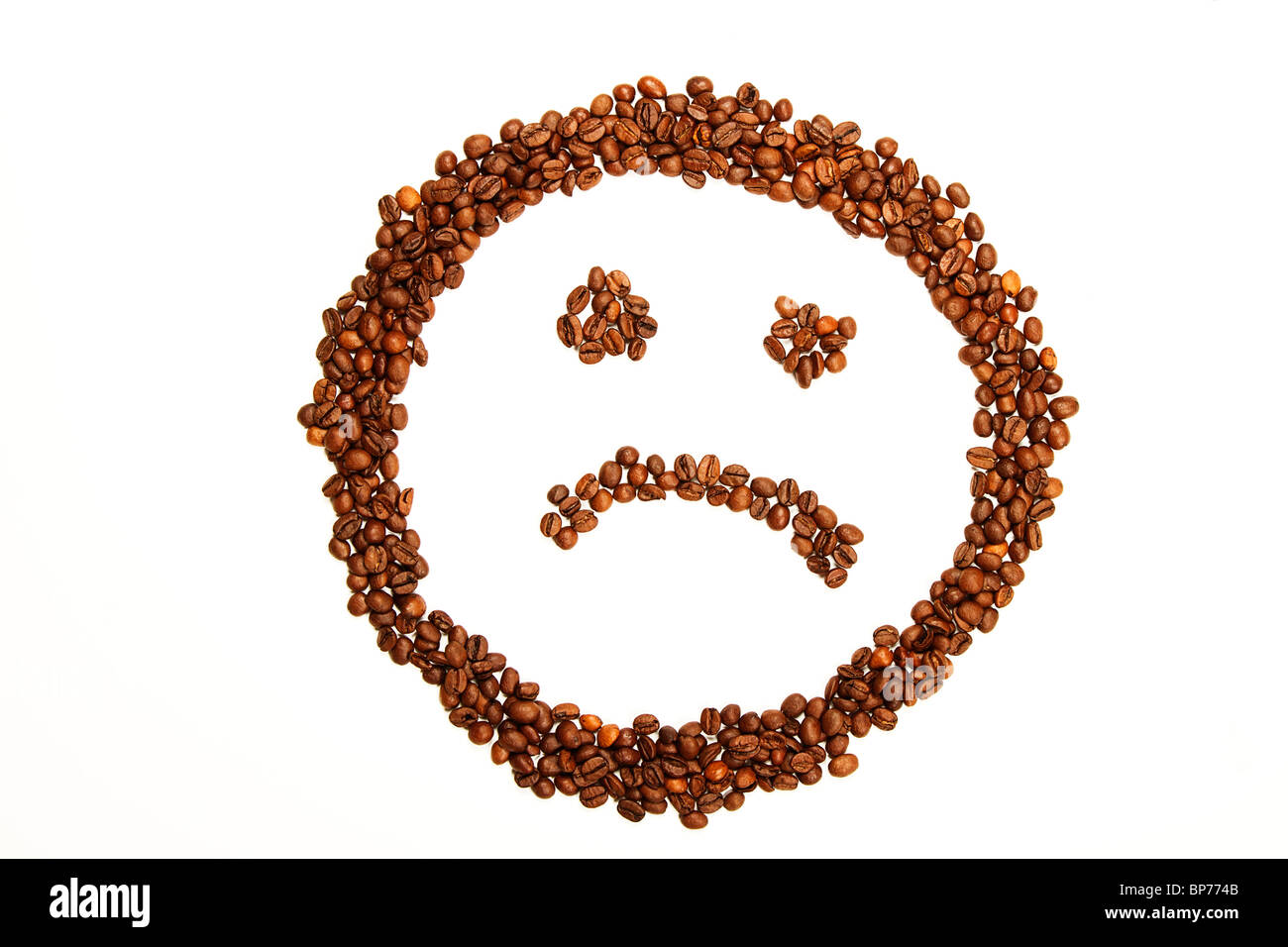 trauriges Smiley, gemacht von Kaffeebohnen auf weißem Hintergrund Stockfoto