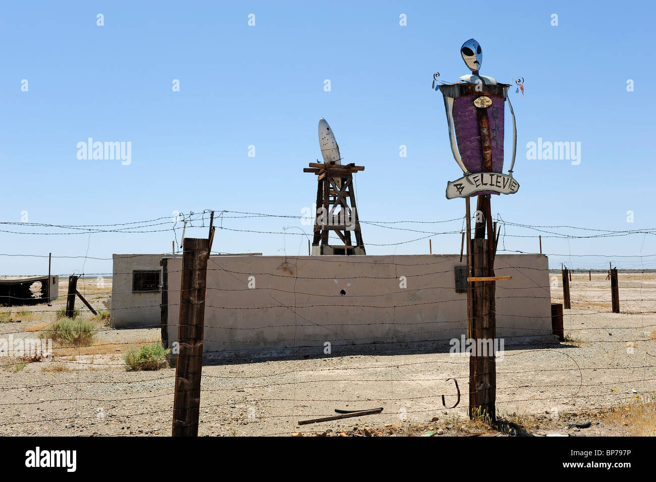 Alien Bildnis mit Silber UFO in der Rückseite Boden Satz vor einem blauen Himmel, das Wort glauben ist unter dem Bildnis gemalt. Stockfoto