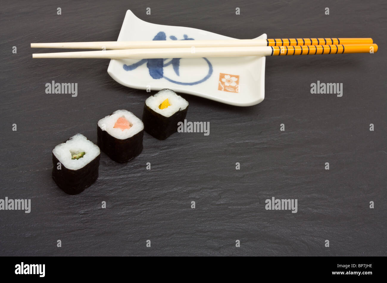 Sushi und Stäbchen auf dunklen grauen Schiefer Hintergrund. Stockfoto