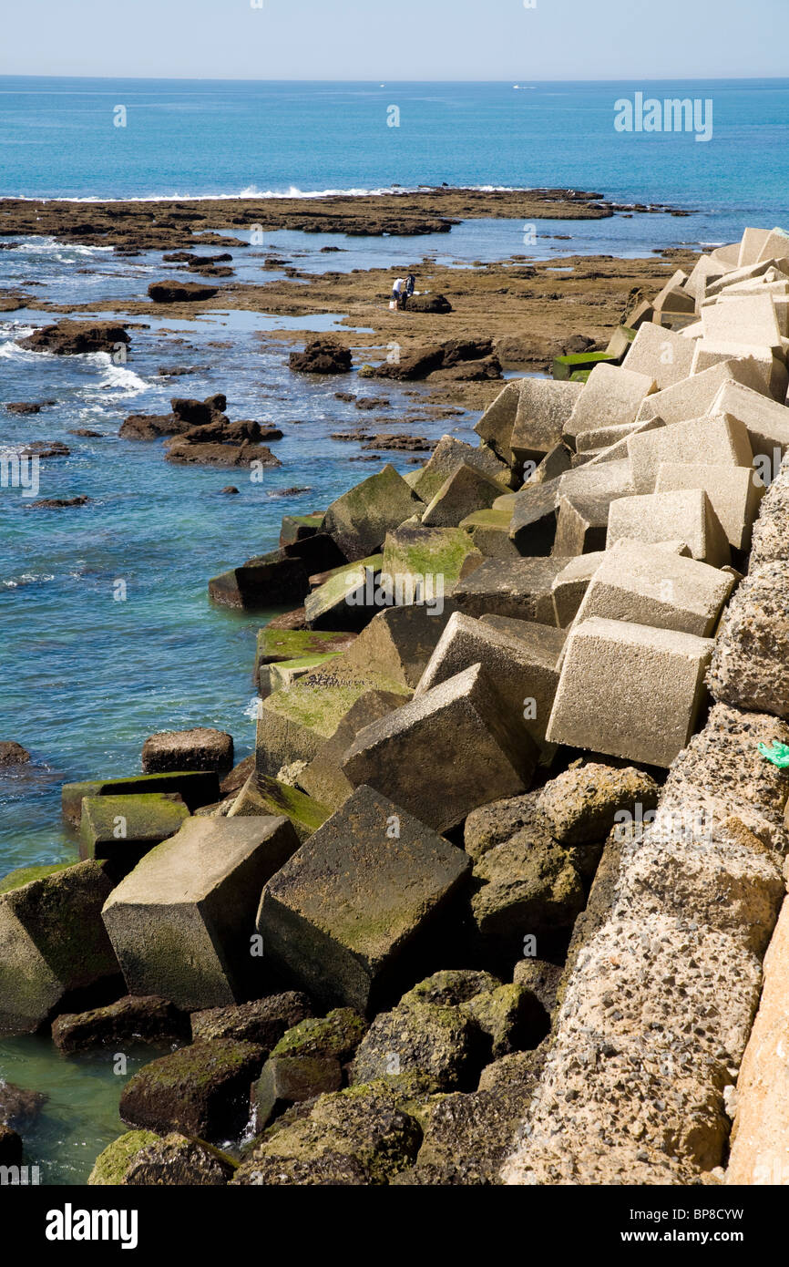 Spanische Meer Abwehr / Verteidigung hergestellt aus Beton und Stein Blöcke / block auf einem Strand von Cadiz. Spanien. Stockfoto