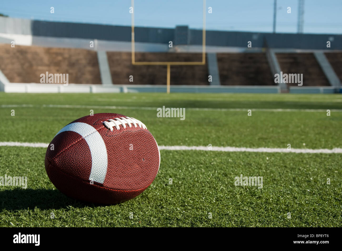 US-amerikanischer American-Football auf Feld mit Torpfosten im Hintergrund. Stockfoto